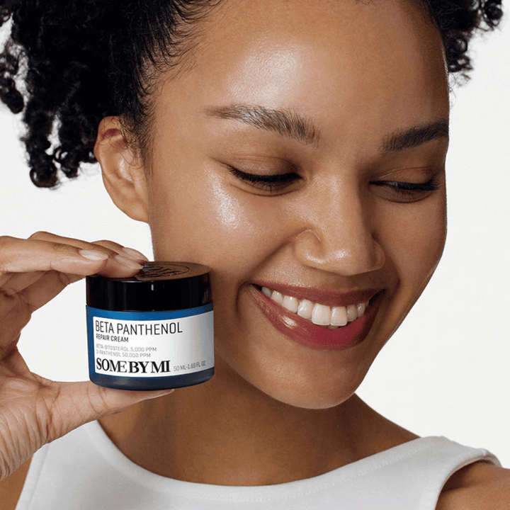 Modell med glowig hud håller i SOME BY MI Beta Panthenol Repair Cream – koreansk ansiktskräm som stärker hudbarriären och återfuktar.
