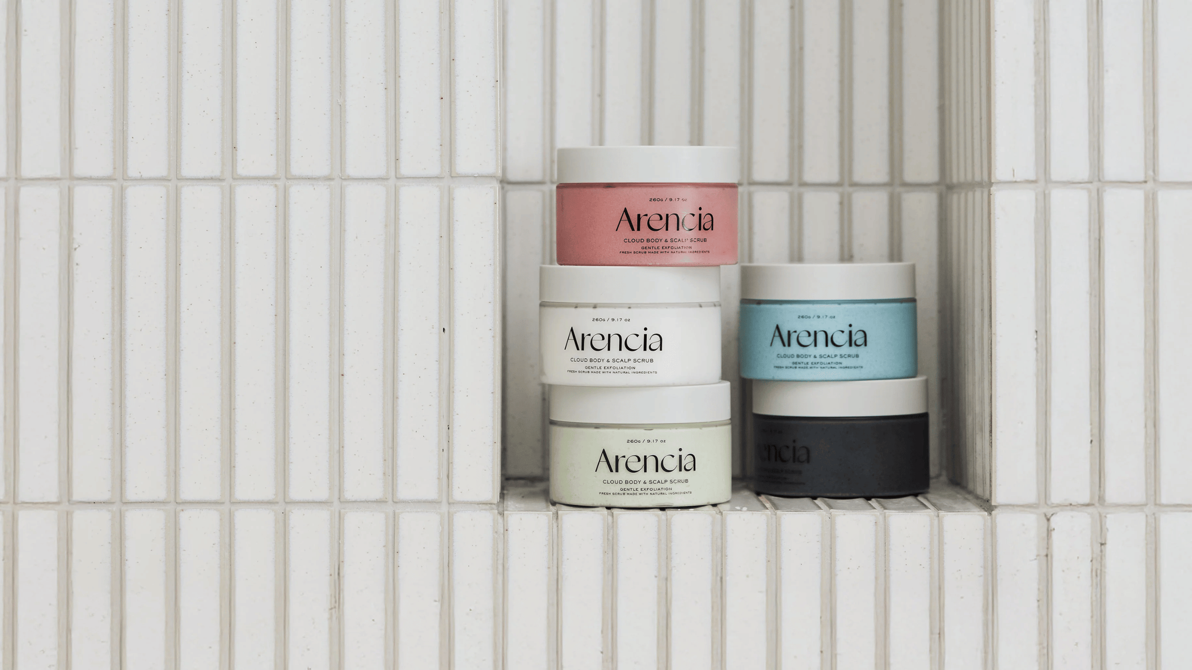 Arencia Cloud Body & Scalp Scrub i flera varianter staplade på kakelhylla. Skonsam kroppsskrubb och skalpskrubb som exfolierar, rengör och ger huden en mjuk och fräsch känsla.