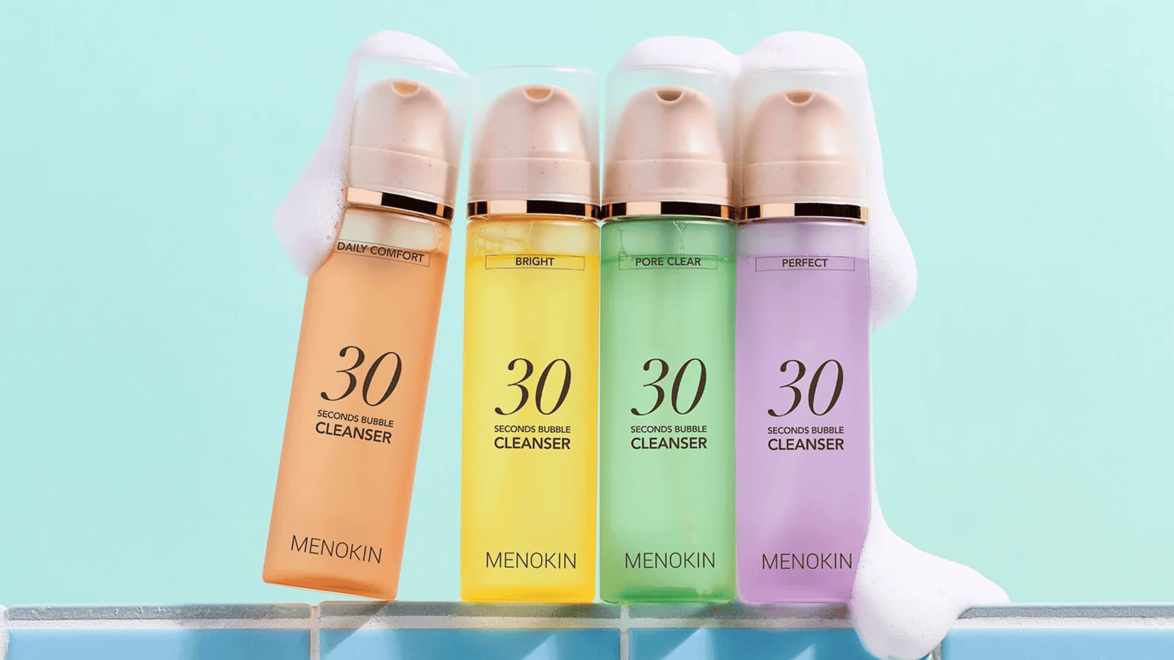 Produktbild som visar fyra varianter av MENOKIN 30 Seconds Bubble Cleanser i olika färger och funktioner: Daily Comfort, Bright, Pore Clear och Perfect. Produkterna står på kaklad yta med mjukt lödder för att framhäva den skummande rengöringen.