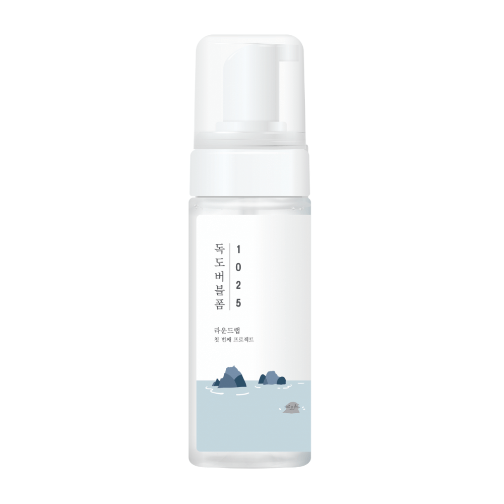 1025 Dokdo Bubble Foam" é um produto de limpeza facial da ROUND LAB, embalado em um frasco de bomba branco com design simples e limpo, adornado com texto e ilustrações minimalistas de paisagens marinhas. 
