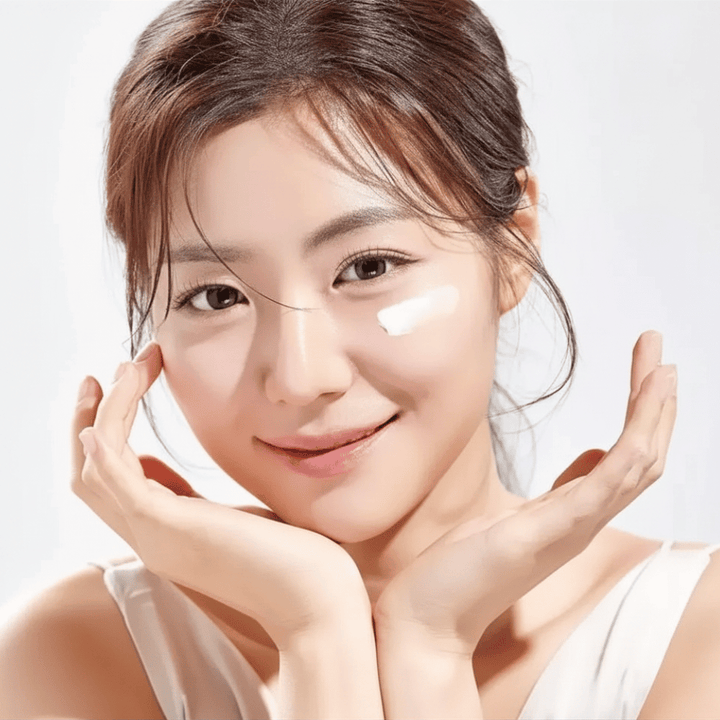Mulher aplica Round Lab 1025 Dokdo Eye Cream sob os olhos para hidratação, luminosidade e um tom de pele mais uniforme