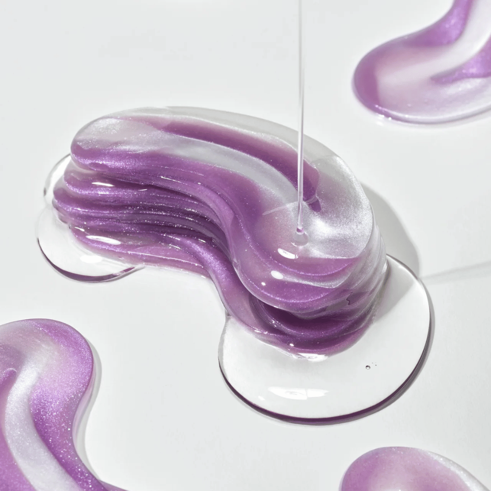 Textura de hidrogel roxo do 360° Shot PDRN Glowing Eye Patch com camadas brilhantes que mostram consistência hidratante e que proporciona brilho para a área dos olhos.