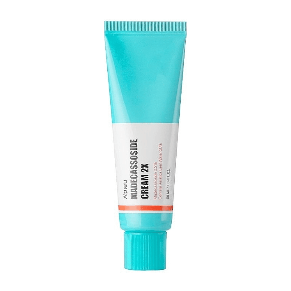 Um tubo com A'PIEU Madecassoside Cream 2X, com uma cor turquesa clara no topo que se transforma em branco na base. O tubo tem texto claro indicando a marca e o nome do produto, bem como o ingrediente ativo Madecassoside 2%. Uma cor de destaque laranja percorre o tubo como uma faixa. O produto parece ser um creme para a pele voltado para cuidados e reparação da pele. O fundo é neutro para manter o foco no produto.