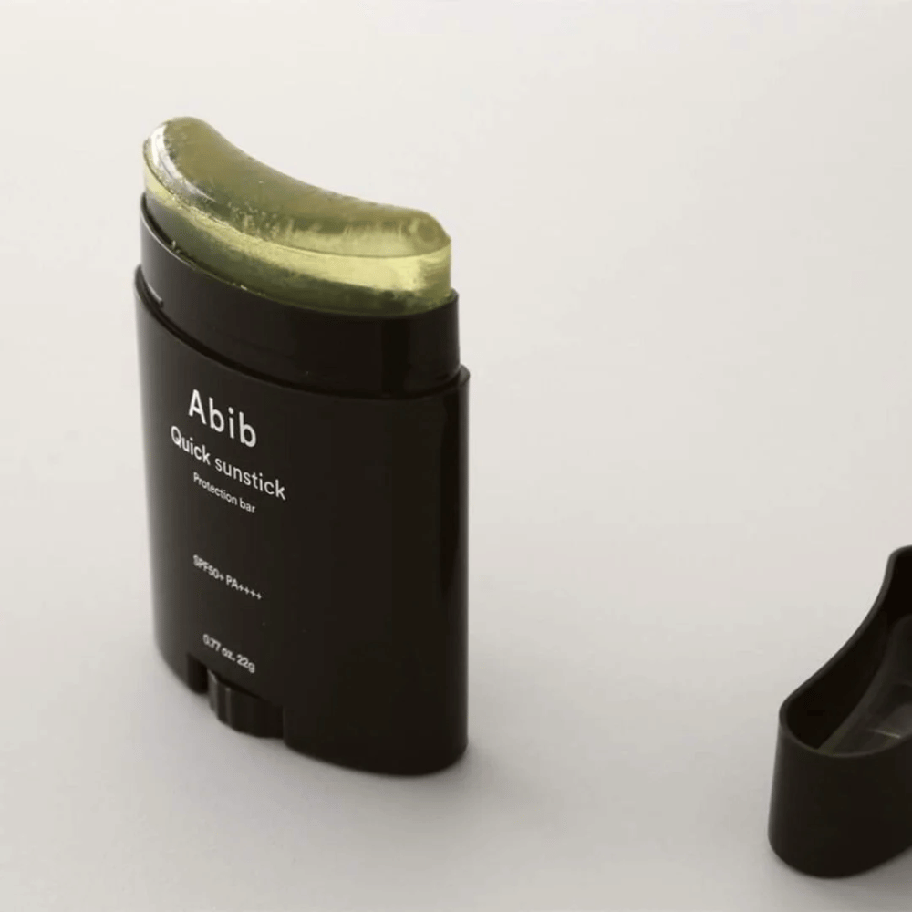 Um tubo preto com tampa verde, contendo Quick Sunstick Protection Bar SPF50+ PA++++ 22g de Abib para proteção solar.