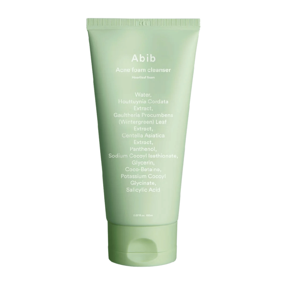 Tubo verde com Abib Acne Foam Cleanser Heartleaf Foam, mostrando ingredientes como Houttuynia Cordata, Centella Asiatica e Ácido Salicílico impressos na frente. O produto está em pé contra um fundo branco.