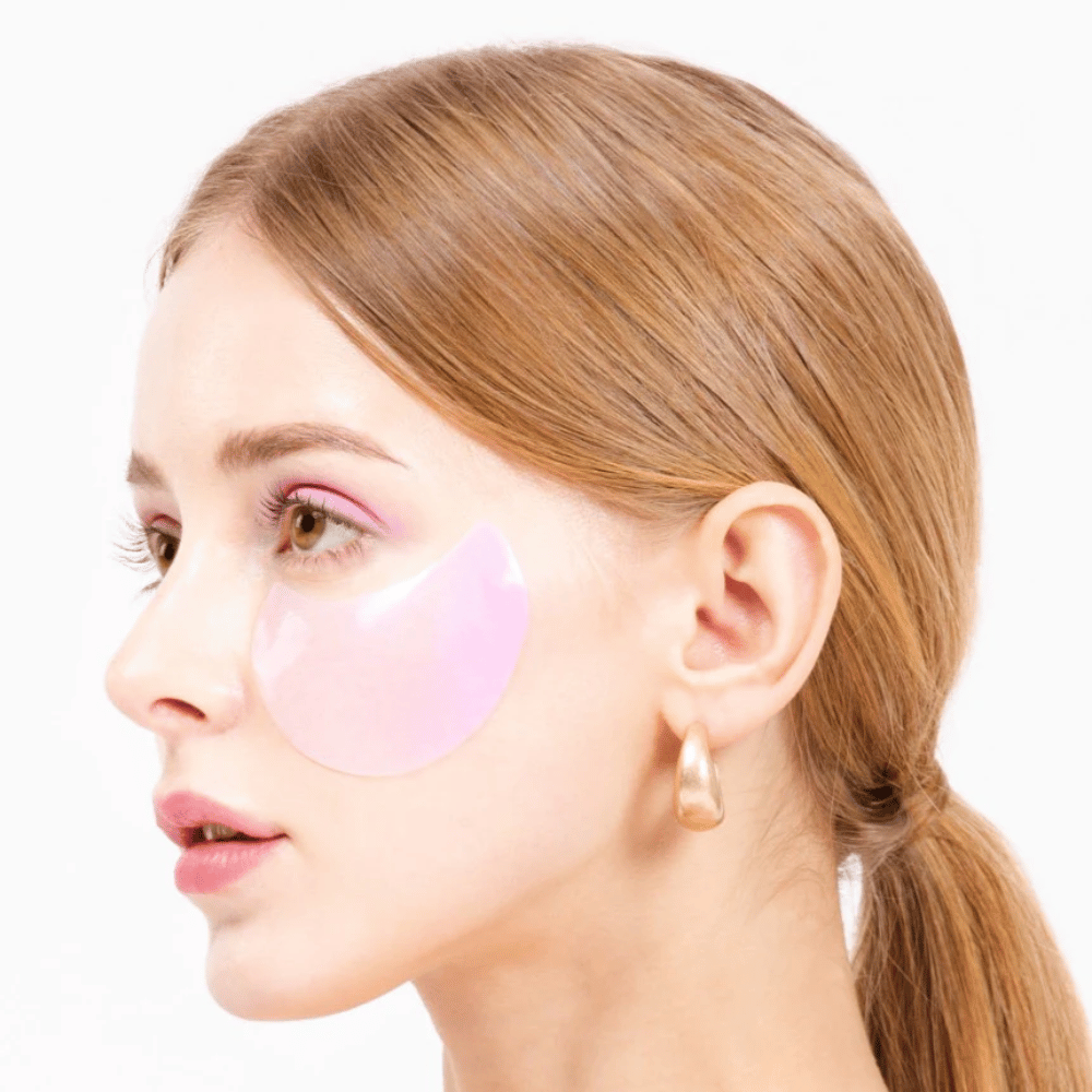 Modelo usa um patch de hidrogel rosa sob o olho, hidratante e rejuvenescedor da pele.