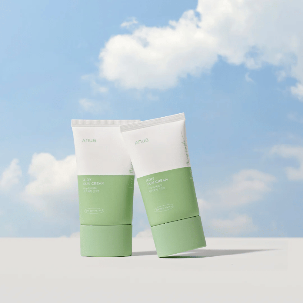 Dois tubos de Anua Airy Sun Cream contra um céu com nuvens brancas.