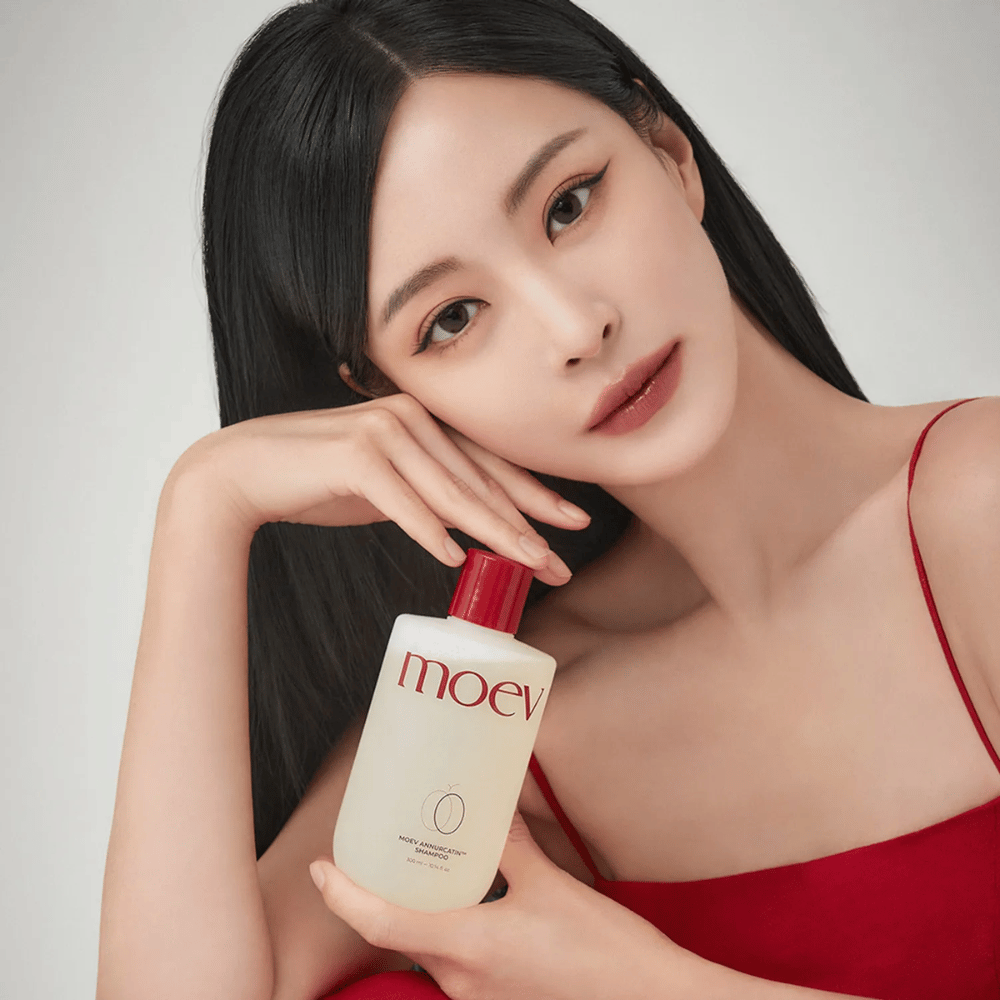 Mulher com cabelo longo e brilhante segura MOEV Annurcatin Shampoo – um champô coreano que hidrata, fortalece e protege o cabelo com ingredientes naturais.
