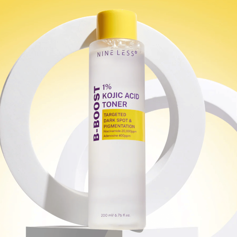 NINE LESS B-Boost 1% Kojic Acid Toner em pé contra fundo amarelo com o texto "Targeted Dark Spot & Pigmentation". Tônico equilibrante de tom de pele com niacinamida e adenosina.