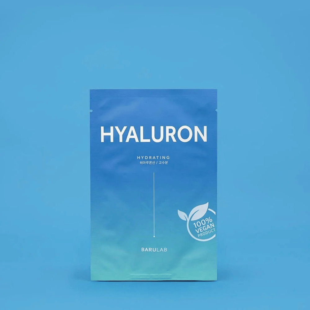 Uma embalagem de BARULAB máscara "HYALURON Hydrating", marcada como "100% Vegan Product", em frente a um fundo azul uniforme. A embalagem tem um gradiente de cor do azul escuro ao azul claro.
