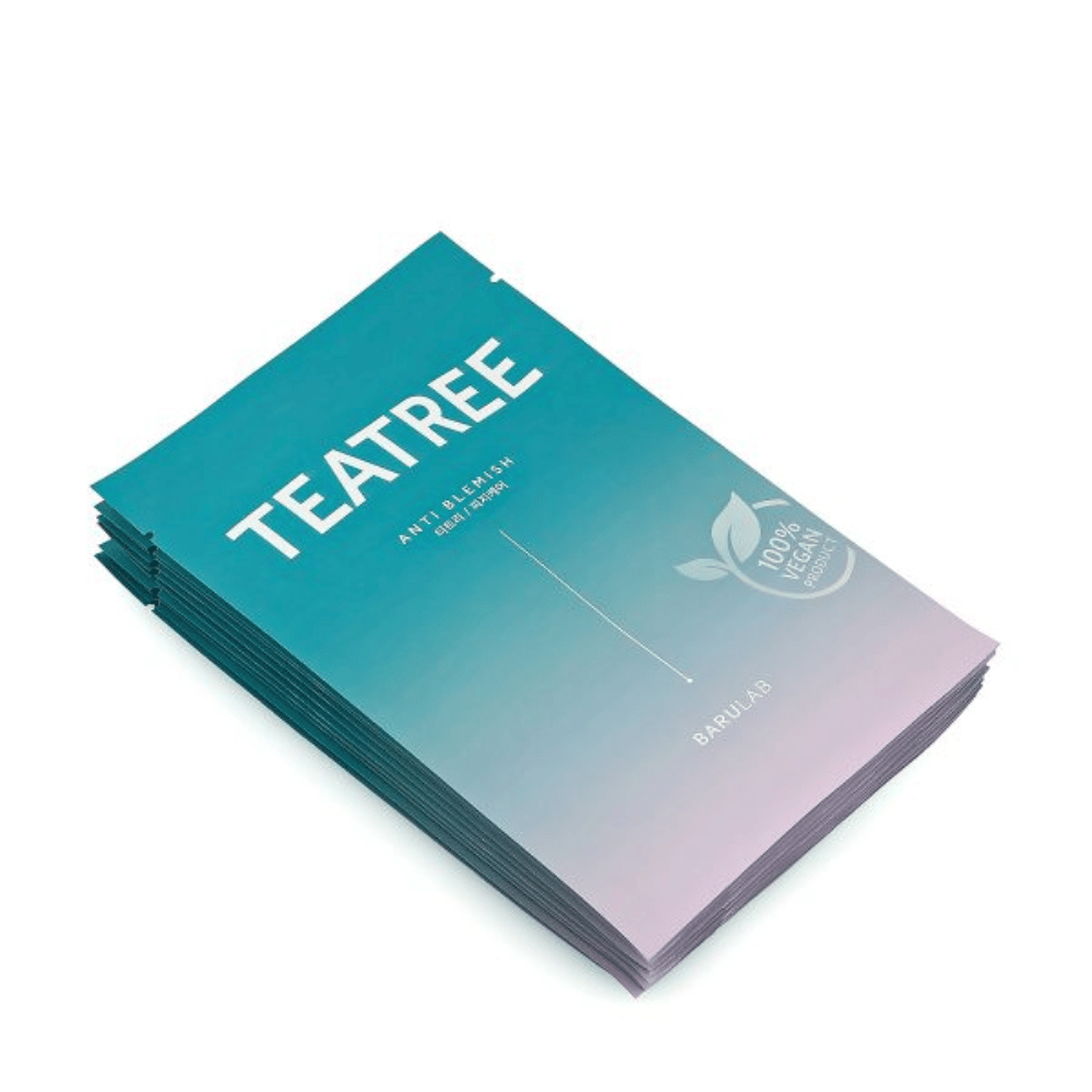 Uma pilha de embalagens de máscaras BARULAB "TEATREE Anti Blemish", todas marcadas como "Produto 100% Vegano". As embalagens têm uma cor turquesa uniforme.
