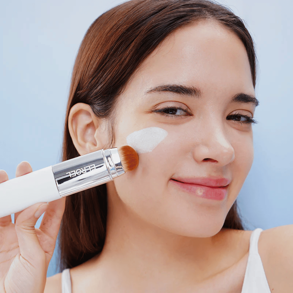 Modelo aplica ELROEL Blanc Cover Cream Stick concealer na bochecha com pincel integrado para cobertura natural e uniforme.
