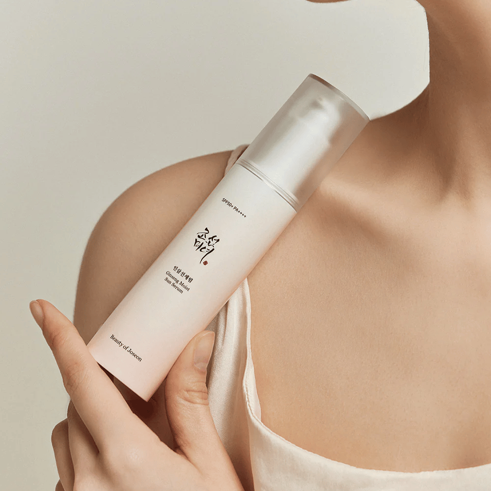 Uma mulher segurando uma garrafa de Beauty of Joseon's Ginseng Moist Sun Serum SPF 50+ PA++++, que oferece proteção de SPF 50+ PA++++ e benefícios para a pele.