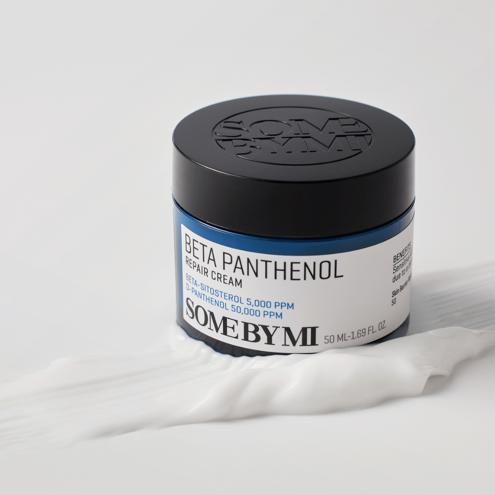 SOME BY MI Beta Panthenol Repair Cream em pote azul colocado sobre textura de creme – creme calmante e hidratante para a pele.