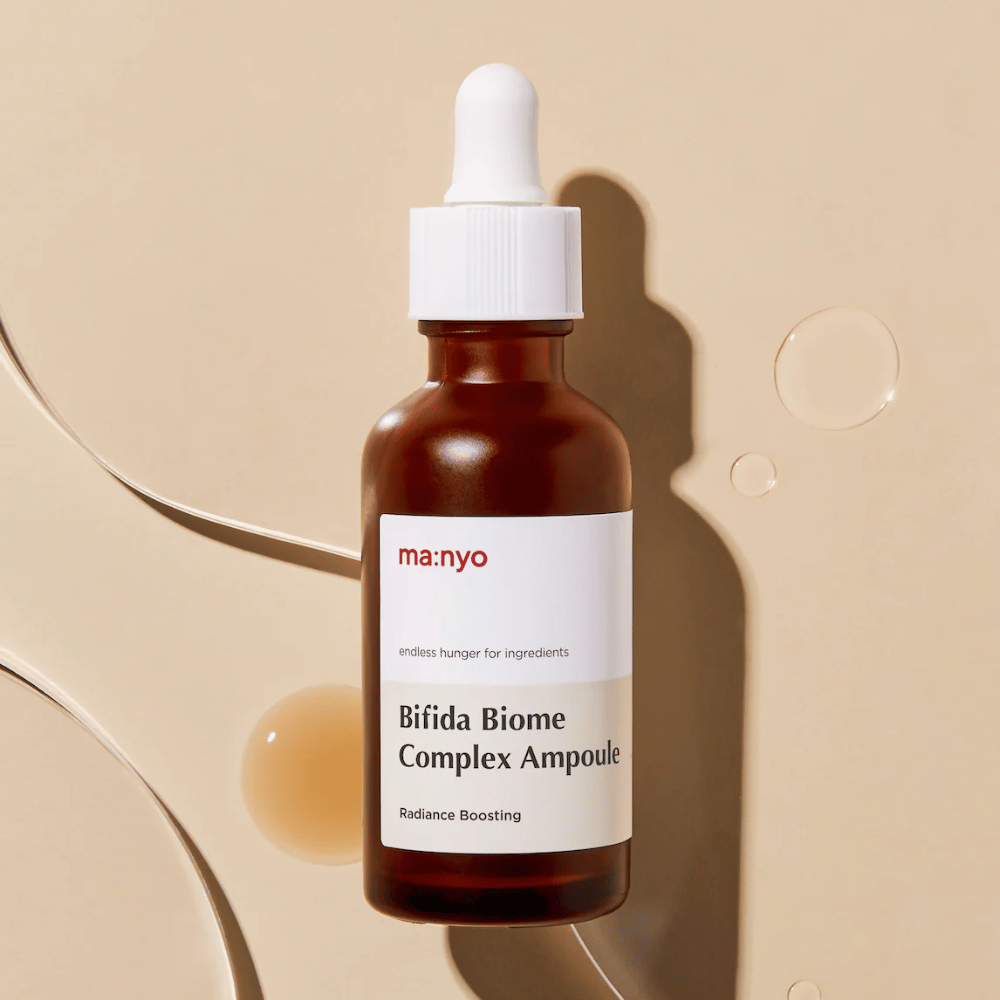 Imagem de produto elegante de ma:nyo Bifida Biome Complex Ampoule com foco no design do frasco e gotas de sérum no fundo.