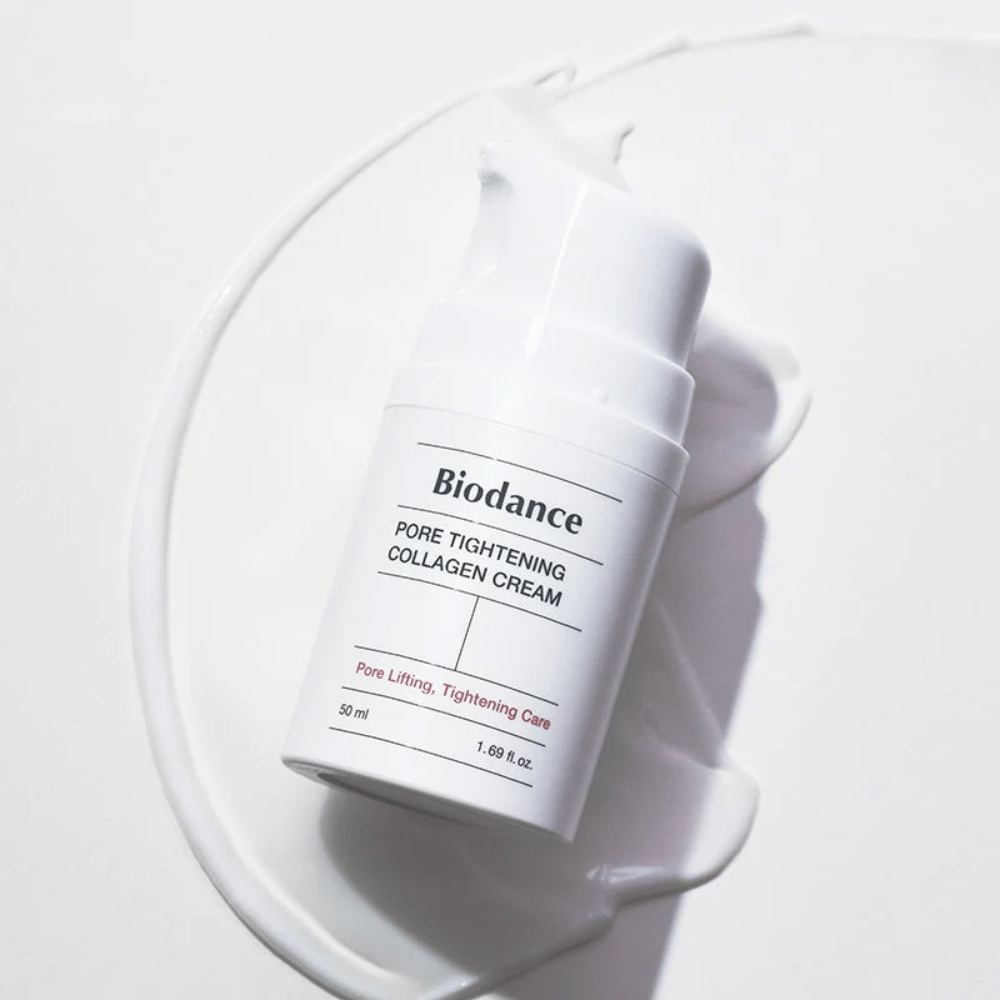 Biodance Pore Tightening Collagen Cream em frasco de bomba branco, deitado sobre um redemoinho de creme branco.