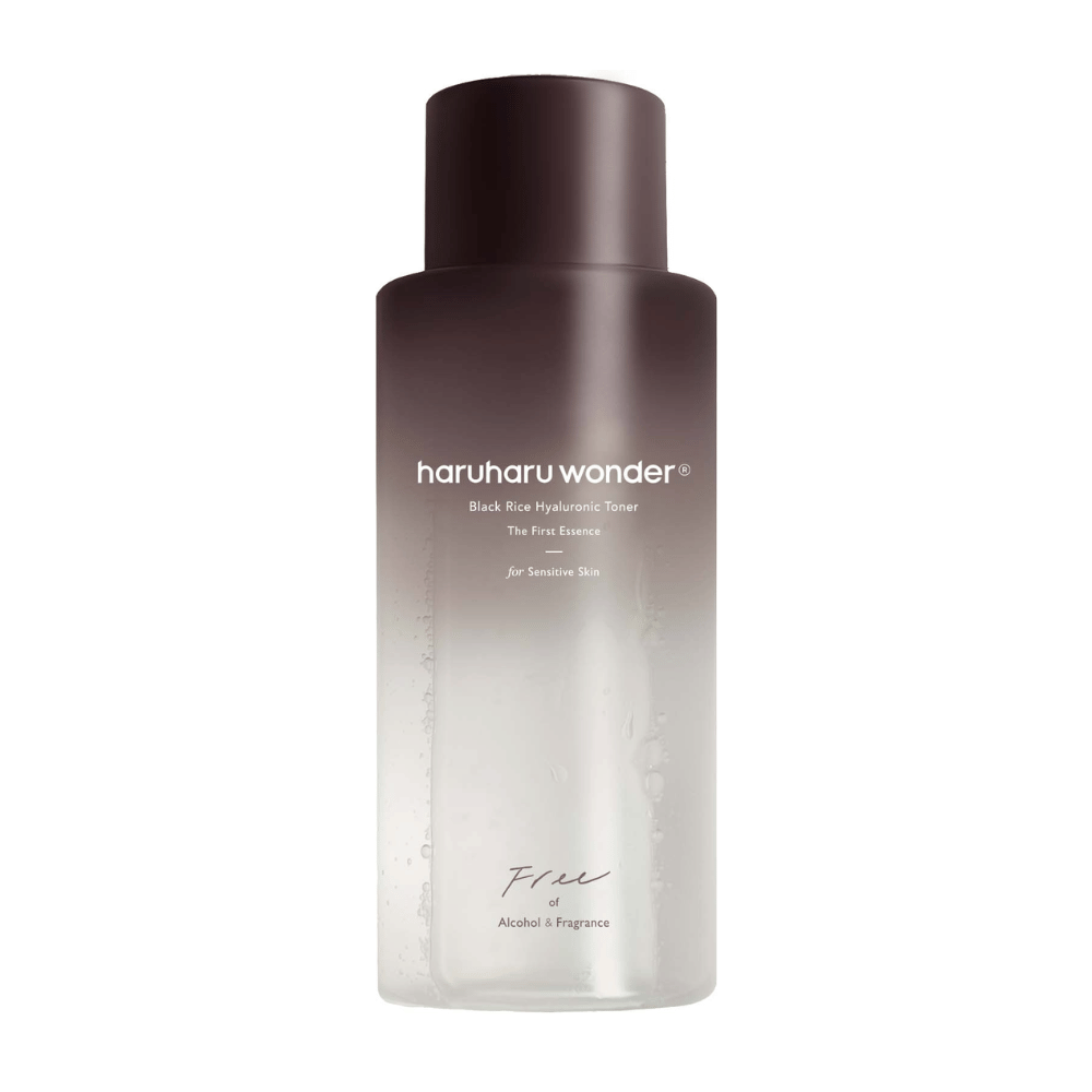 Uma garrafa de haruharu wonder Black Rice Hyaluronic Toner The First Essence, com gradiente de marrom escuro a transparente e o texto "Free of Alcohol & Fragrance", em fundo branco.