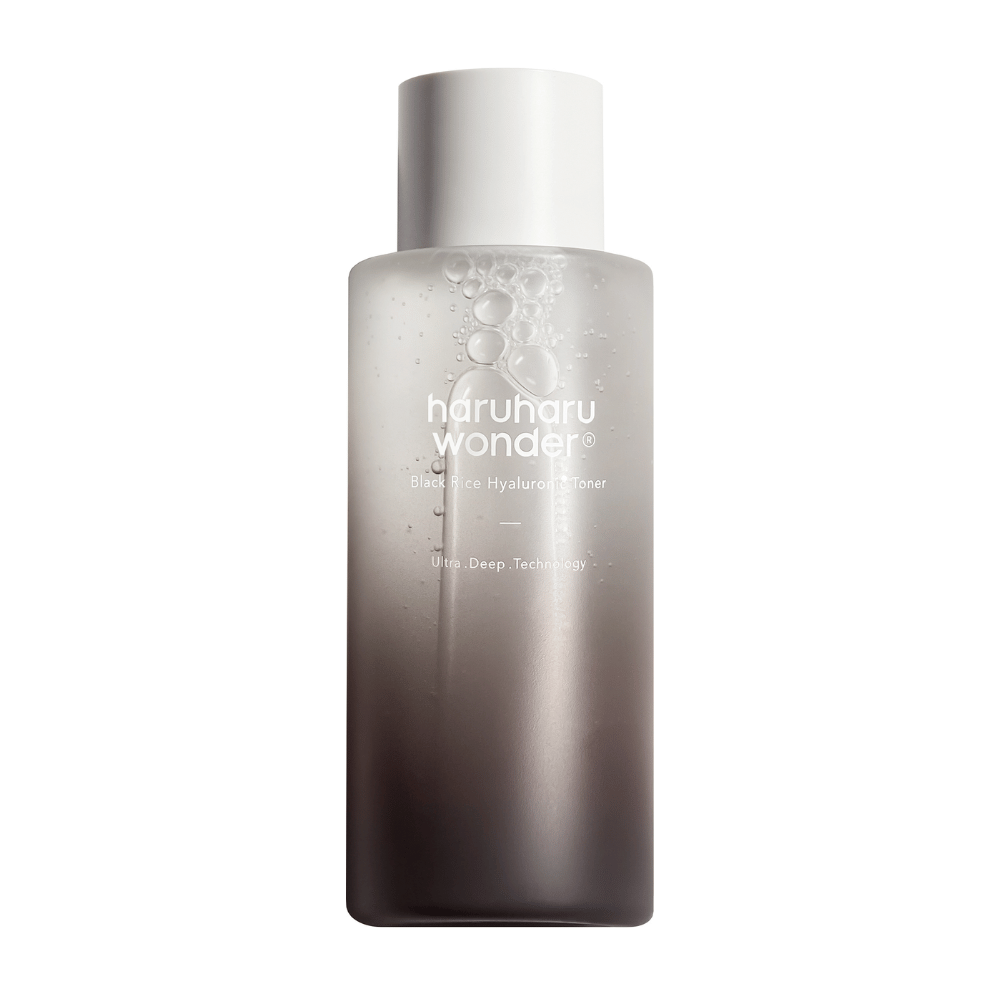 Uma garrafa de haruharu wonder Black Rice Hyaluronic Toner com um gradiente de cor de cinza a branco e gotas de água na superfície, contra um fundo branco.