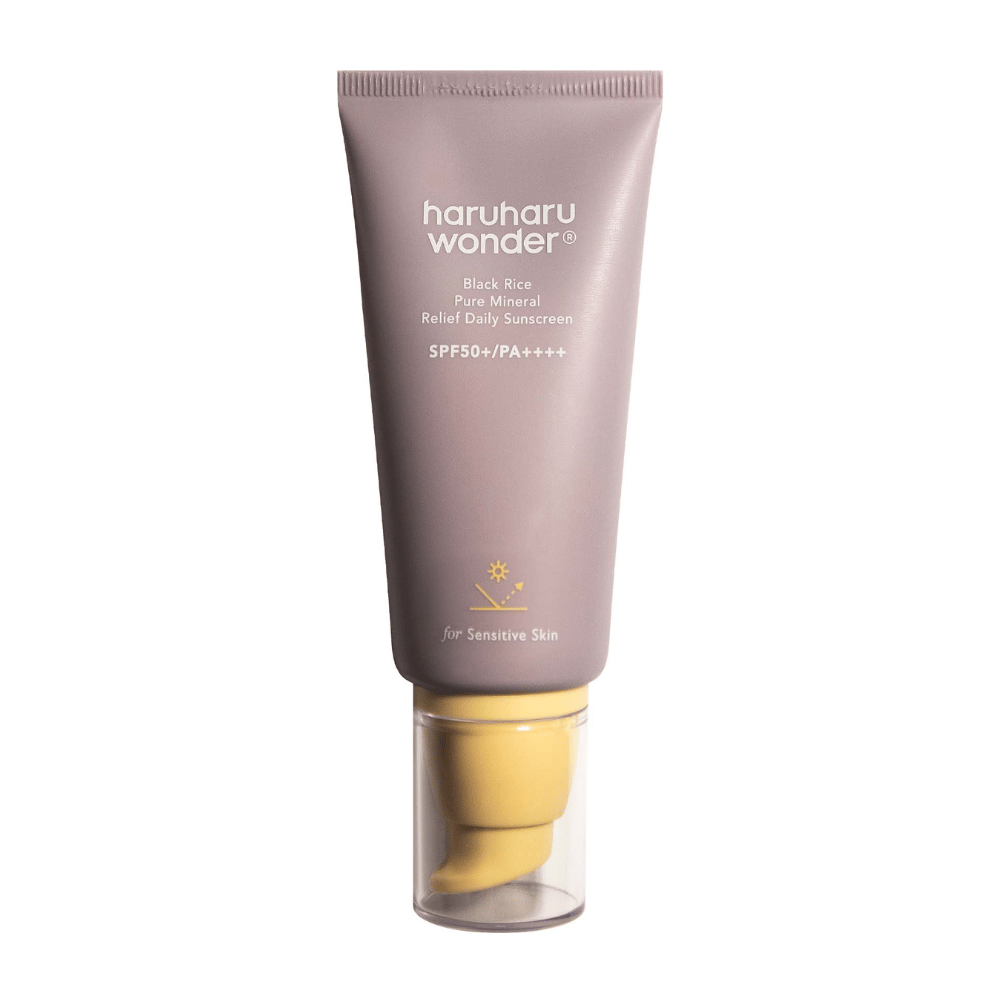 Um tubo lilás com Haruharu Wonder Black Rice Pure Mineral Relief Daily Sunscreen SPF 50+ PA++++. O tubo tem uma tampa transparente e texto que descreve o alto nível de proteção do protetor solar, especialmente adaptado para pele sensível.
