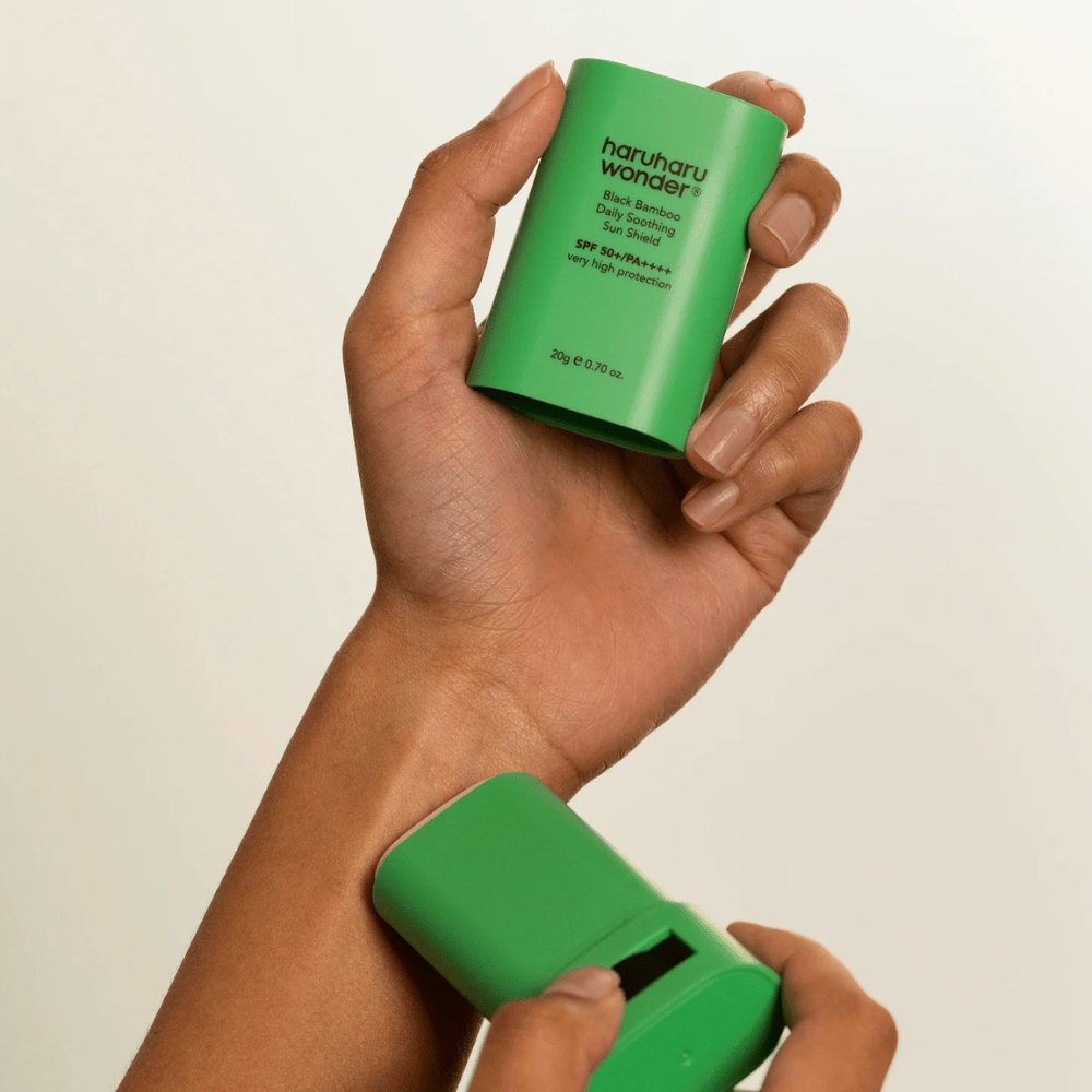 Uma pessoa aplica Haruharu Wonder Black Bamboo Daily Soothing Sun Shield – um protetor solar em stick verde com SPF 50+ PA++++ – no pulso.