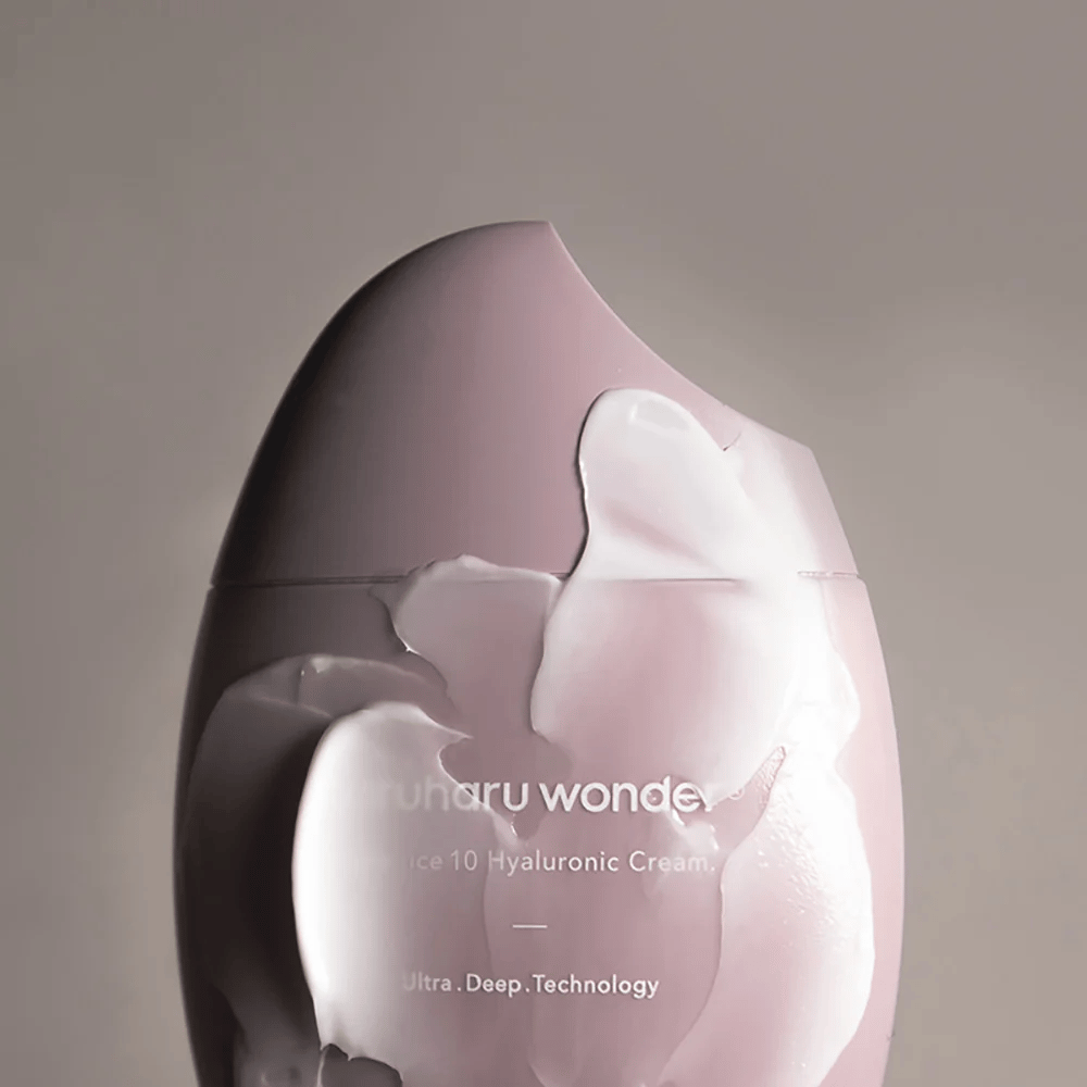 A imagem mostra um pote de "Haruharu Wonder Black Rice 10 Hyaluronic Cream", que está parcialmente coberto por um creme espesso e transparente. O texto na imagem sugere o uso de tecnologia avançada para hidratação profunda da pele. O design é moderno e minimalista.