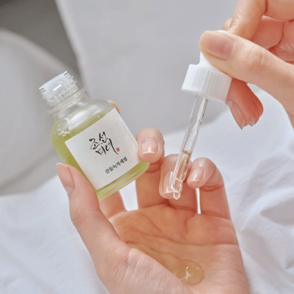 Mão pingando Beauty of Joseon Calming Serum Chá Verde + Pantenol na pele – sérum coreano calmante para pele sensível.