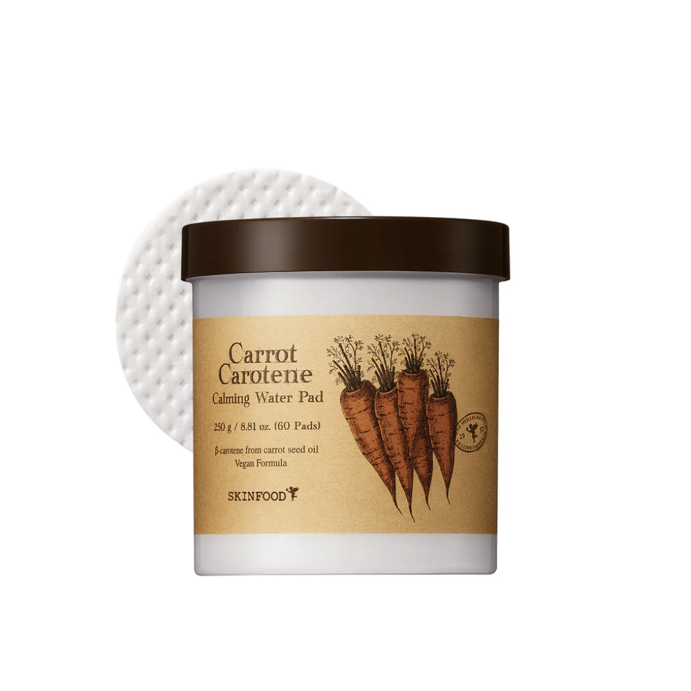Um frasco "Carrot Carotene Calming Water Pad" de SKINFOOD. O frasco contém 60 pads e é marcado com uma imagem de cenouras. O produto, que é à base de óleo de semente de cenoura, é amigo dos veganos e projetado para acalmar a pele.