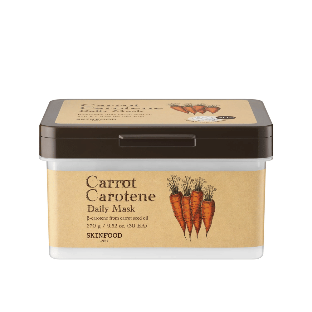 Uma embalagem "Carrot Carotene Daily Mask" de SKINFOOD, contendo 30 máscaras faciais. O produto é enriquecido com β-caroteno de óleo de semente de cenoura e é projetado para uso diário. A embalagem é robusta com um rótulo de inspiração vintage que destaca as cenouras como ingrediente principal.