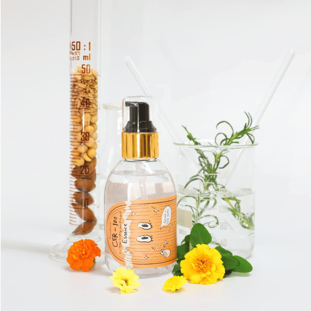 CER-100 Hair Essence juntamente com flores e vidro de laboratório que destacam os ingredientes e o cuidado capilar.