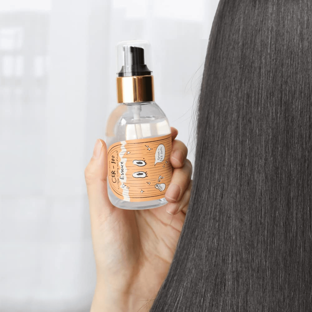 Pessoa segura CER-100 Hair Essence ao lado de cabelo comprido e brilhante para mostrar suavidade e cuidado.