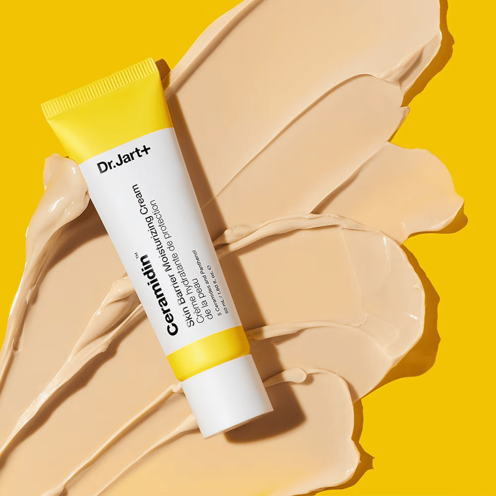 Tubo com Dr. Jart+ Ceramidin Skin Barrier Moisturizing Cream contra um fundo amarelo com creme espalhado.