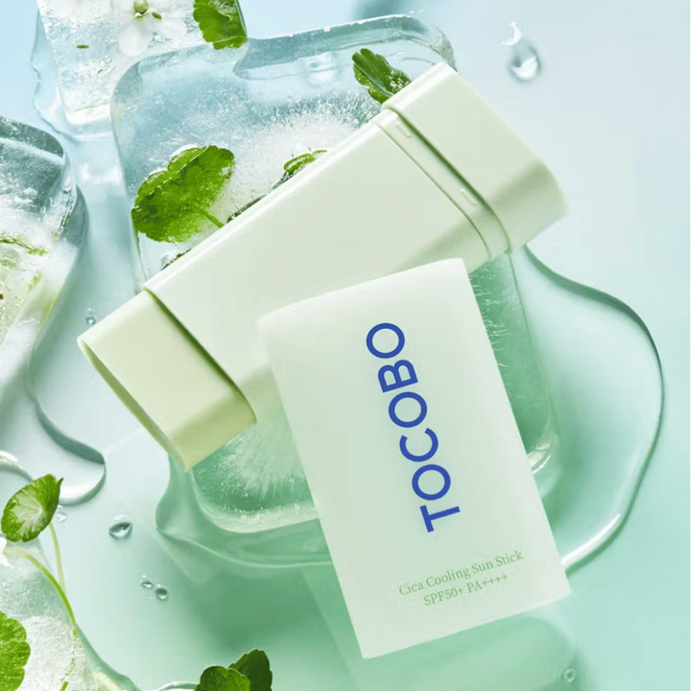 Tocobo Cica Cooling Sun Stick SPF50+ PA++++ em cubos de gelo com folhas de plantas verdes, transmitindo uma sensação refrescante e revigorante.