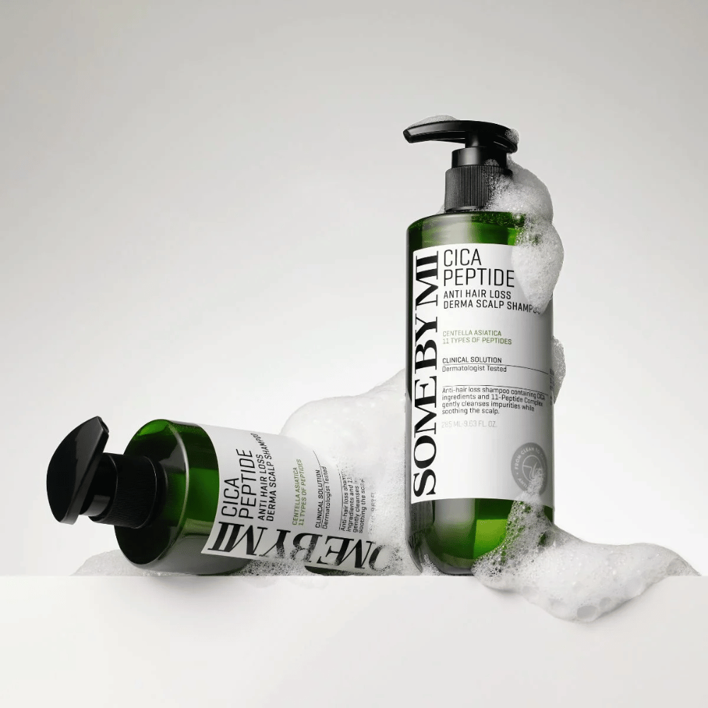 Duas garrafas de SOME BY MI Cica Peptide Anti Hair Loss Derma Scalp Shampoo cobertas de espuma, em pé e deitadas contra um fundo branco.