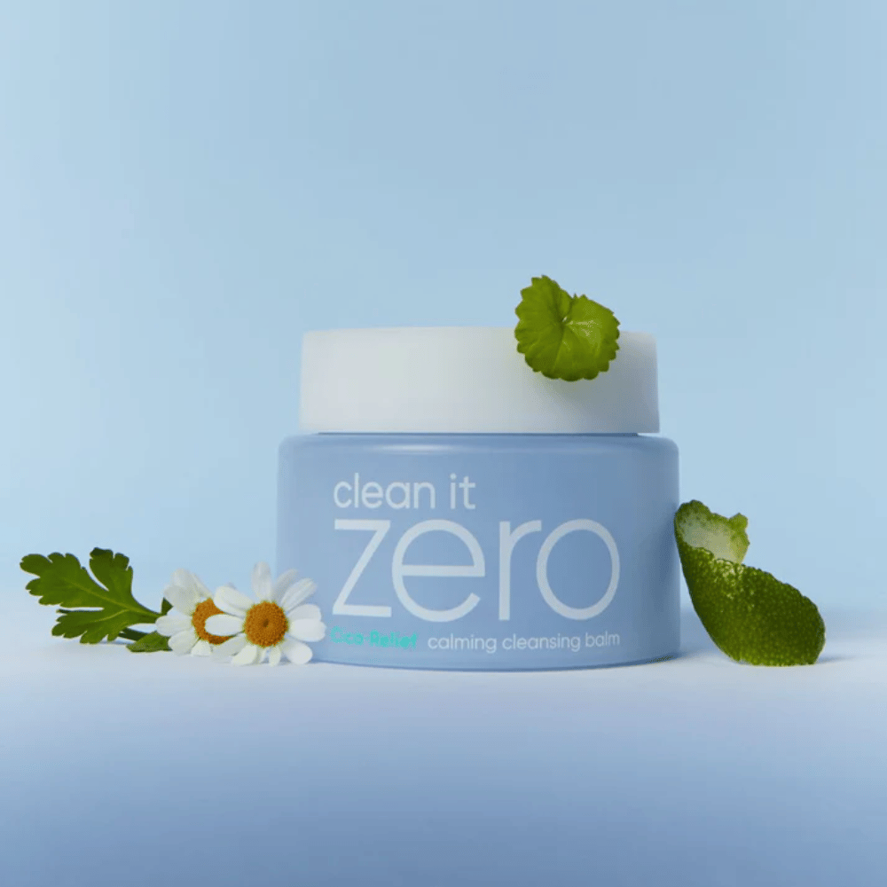 Clean It Zero Cica-Relief Calming Cleansing Balm colocado com plantas e flores, ilustra limpeza suave com CICA calmante para pele sensível e irritada.