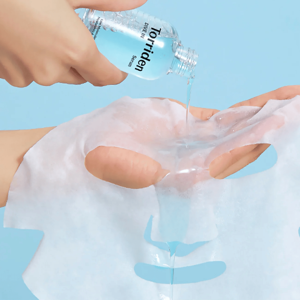 Máscara facial dr embebida em solução de uma garrafa "Torriden Dive-In", contra fundo azul.