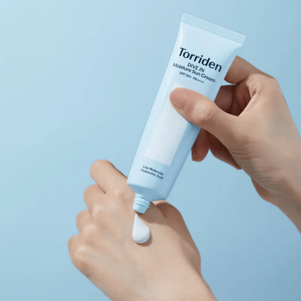 Torriden DIVE-IN Moisture Sun Cream SPF50+ PA++++ aplicado na mão para mostrar a textura leve e cremosa do protetor solar hidratante.