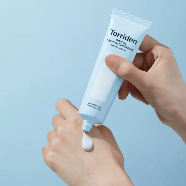 Torriden DIVE-IN Moisture Sun Cream SPF50+ PA++++ aplicado na mão para mostrar a textura leve e cremosa do protetor solar hidratante.