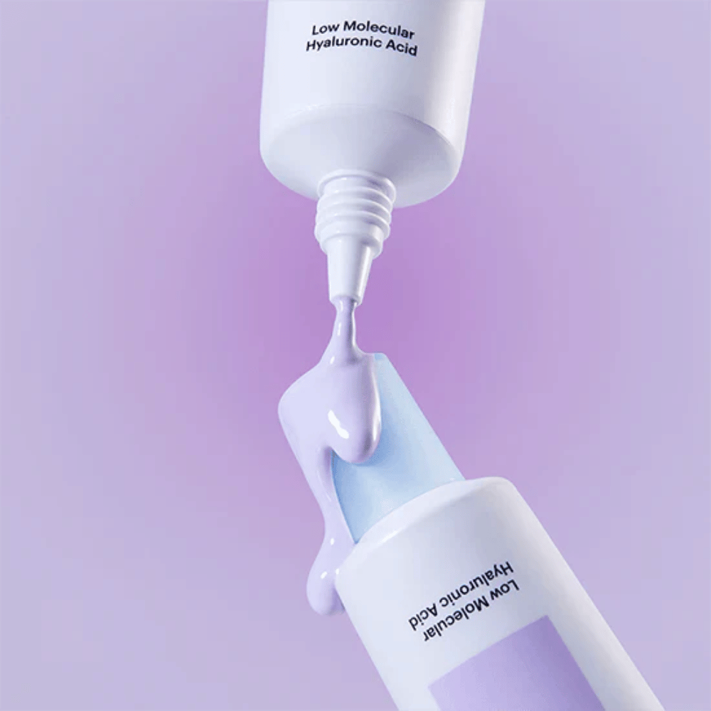 Grande plano de Torriden DIVE IN Tone Up Sun Cream Purple onde o creme lilás é aplicado a partir do tubo para ilustrar a consistência do produto.