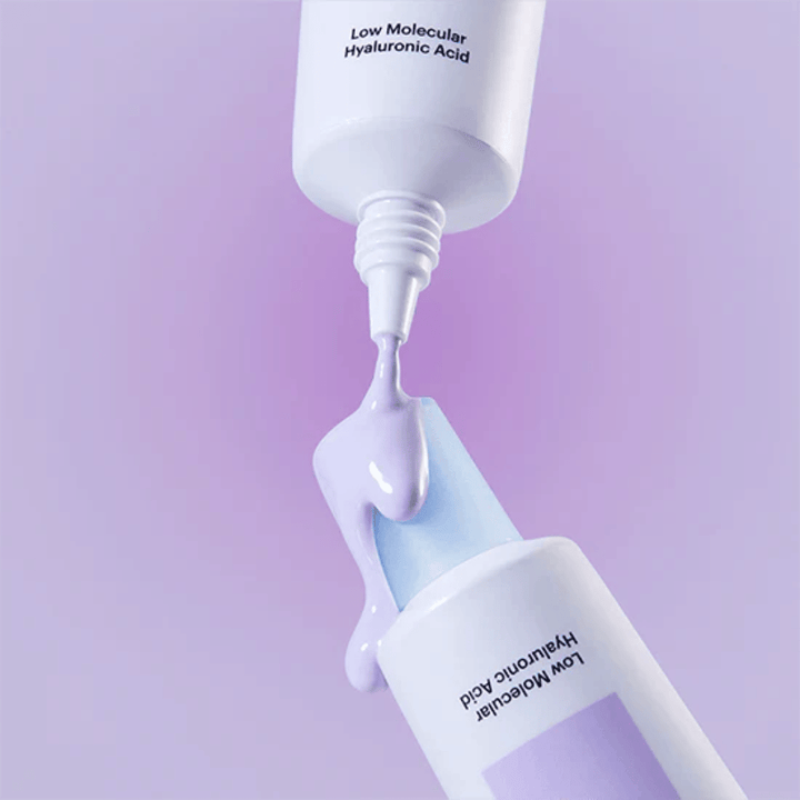 Grande plano de Torriden DIVE IN Tone Up Sun Cream Purple onde o creme lilás é aplicado a partir do tubo para ilustrar a consistência do produto.