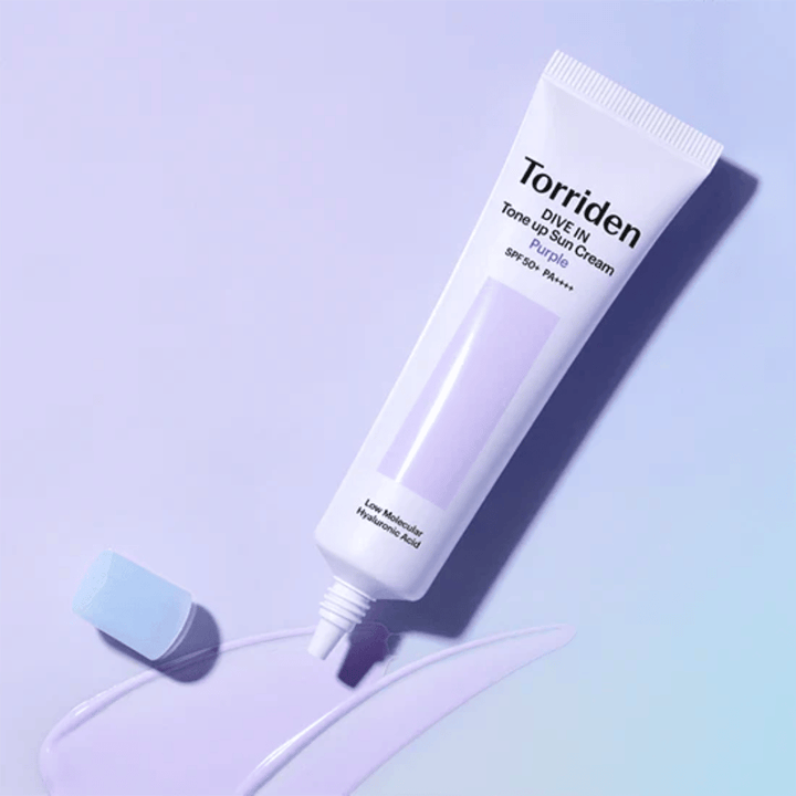 Tubo aberto de Torriden DIVE IN Tone Up Sun Cream Purple com textura de protetor solar de tom lilás que mostra a fórmula corretora de cor do produto.