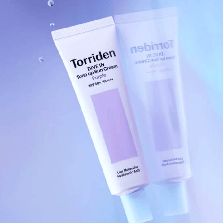 Torriden DIVE IN Tone Up Sun Cream Purple SPF50+ PA++++ fotografada sobre um fundo lilás suave que destaca o design refletor de luz do produto.
