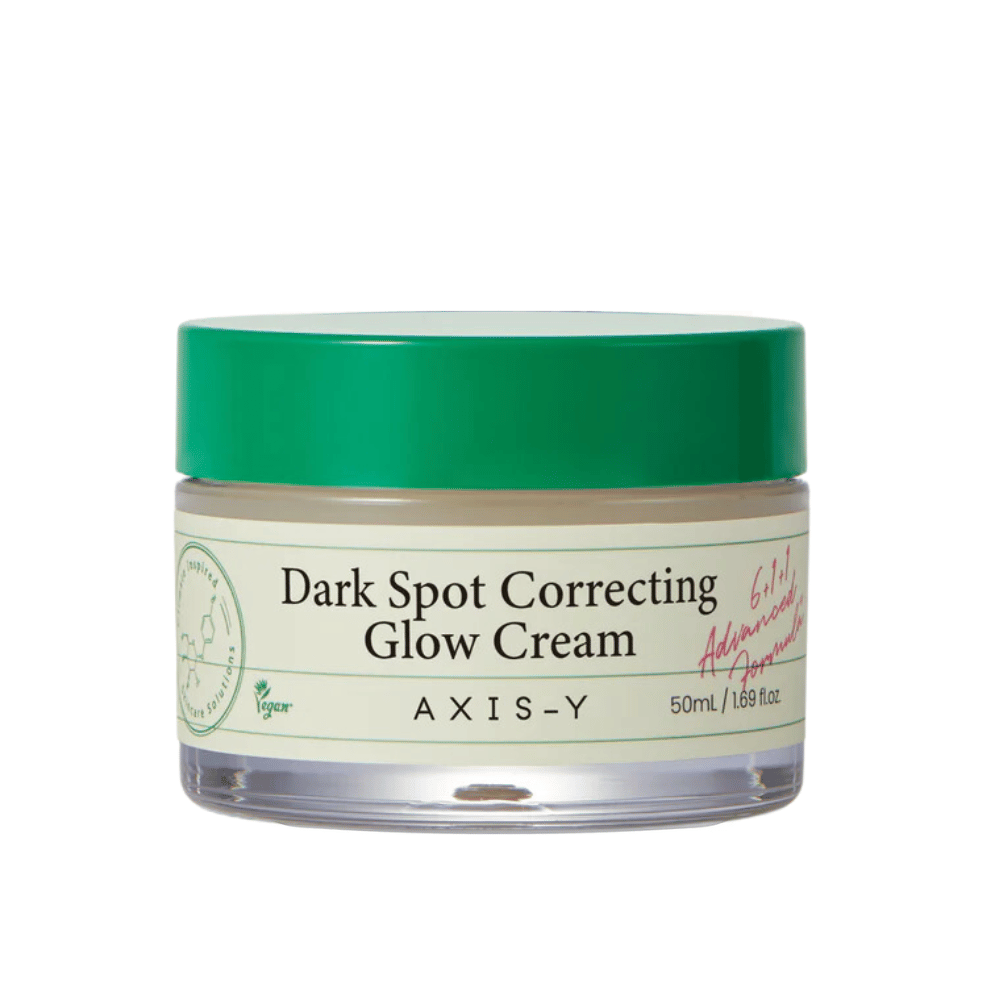 Um frasco de "AXIS-Y Dark Spot Correcting Glow Cream". Este creme é destinado a corrigir manchas escuras e dar brilho à pele. A embalagem é elegante com uma base transparente e uma tampa verde chamativa.