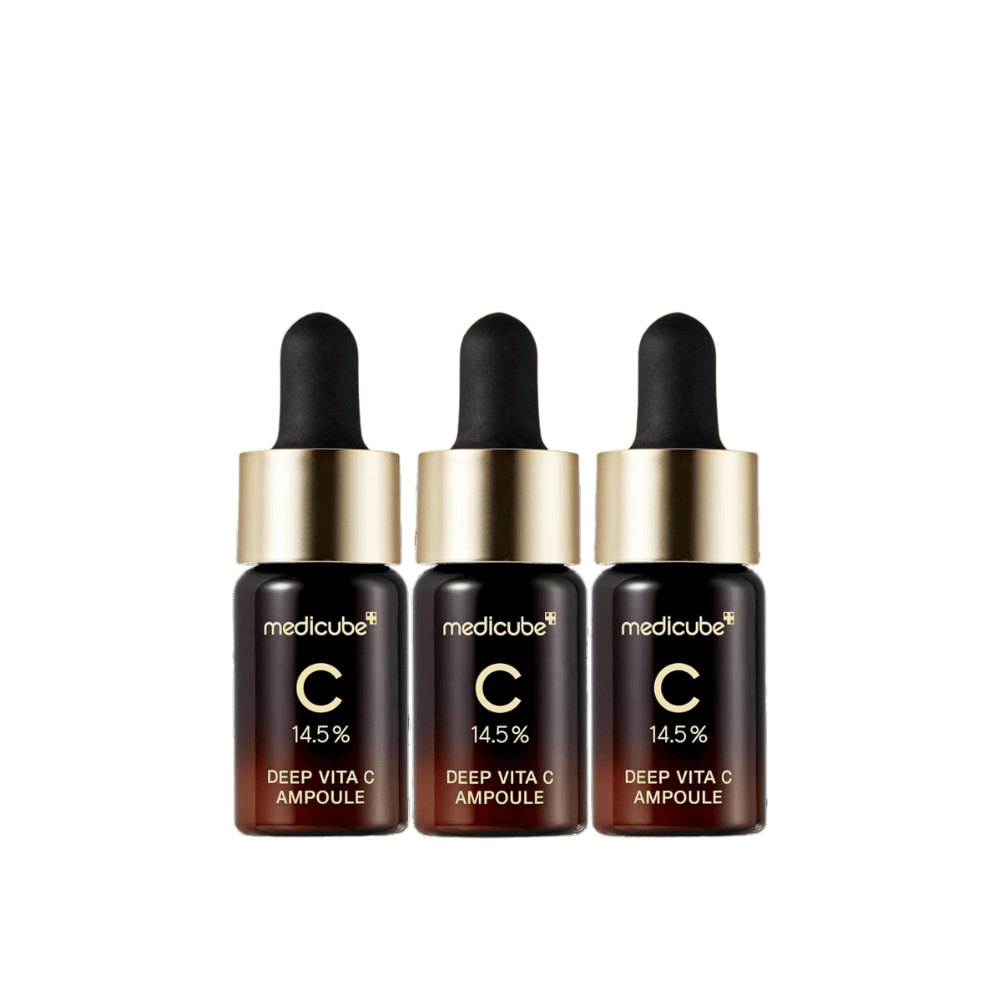 Três garrafas de Medicube Deep Vita C Ampoule, com 14,5 % de vitamina C, dispostas em fila. As garrafas têm um design elegante com base marrom escura e tampa dourada. Perfeito para um tom de pele mais claro e uma textura de pele mais uniforme.