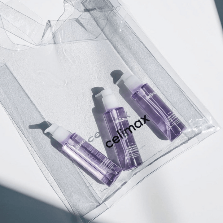Tre flaskor av Celimax Derma Nature Fresh Blackhead Jojoba Cleansing Oil i lila förpackning, placerade i en transparent påse med logotypen 'celimax'.