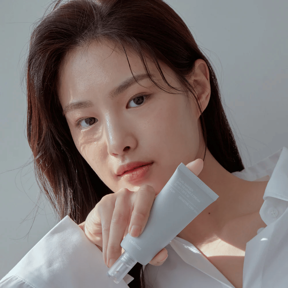 Modelo segurando Celimax Dual Barrier Skin Wearable Cream, creme facial calmante e que fortalece a barreira para pele sensível e seca.