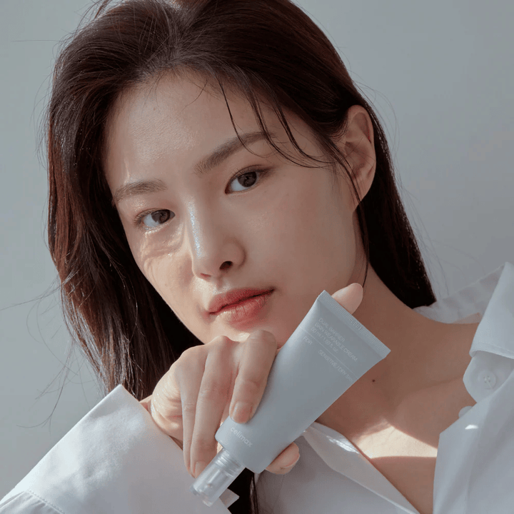 Modelo segurando Celimax Dual Barrier Skin Wearable Cream, creme facial calmante e que fortalece a barreira para pele sensível e seca.