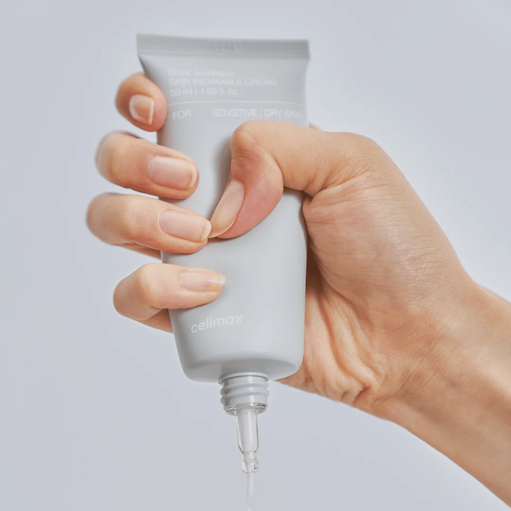 Mão aplicando Celimax Dual Barrier Skin Wearable Cream, creme facial que fortalece a barreira para pele sensível e seca que proporciona hidratação duradoura e protege a barreira da pele.