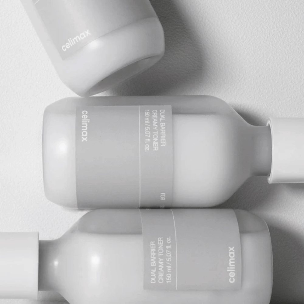Três garrafas deitadas de Celimax Dual Barrier Creamy Toner num design minimalista com rótulo cinza e luz suave – perfeito para pele sensível e seca.