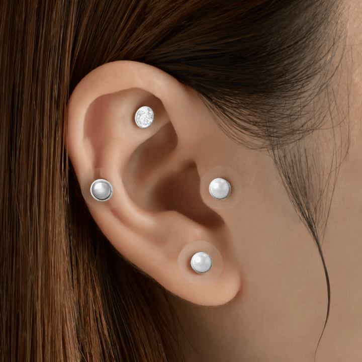 Plano aproximado de uma orelha com vários RETURNITY Ear Therapy Acupressure Patch aplicados em diferentes áreas da orelha para acupressão e um visual elegante.