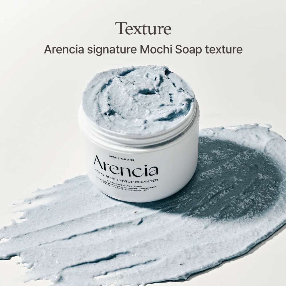 Frasco aberto com Arencia Fresh Blue Hyssop Rice Mochi Cleanser, colocado sobre uma camada espalhada da fórmula de limpeza cremosa azul que mostra sua textura semelhante a mochi.